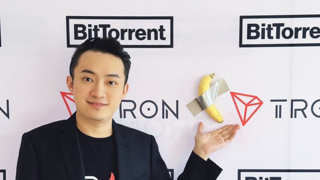 Justin Sun standing beside a banana taped to a wall.